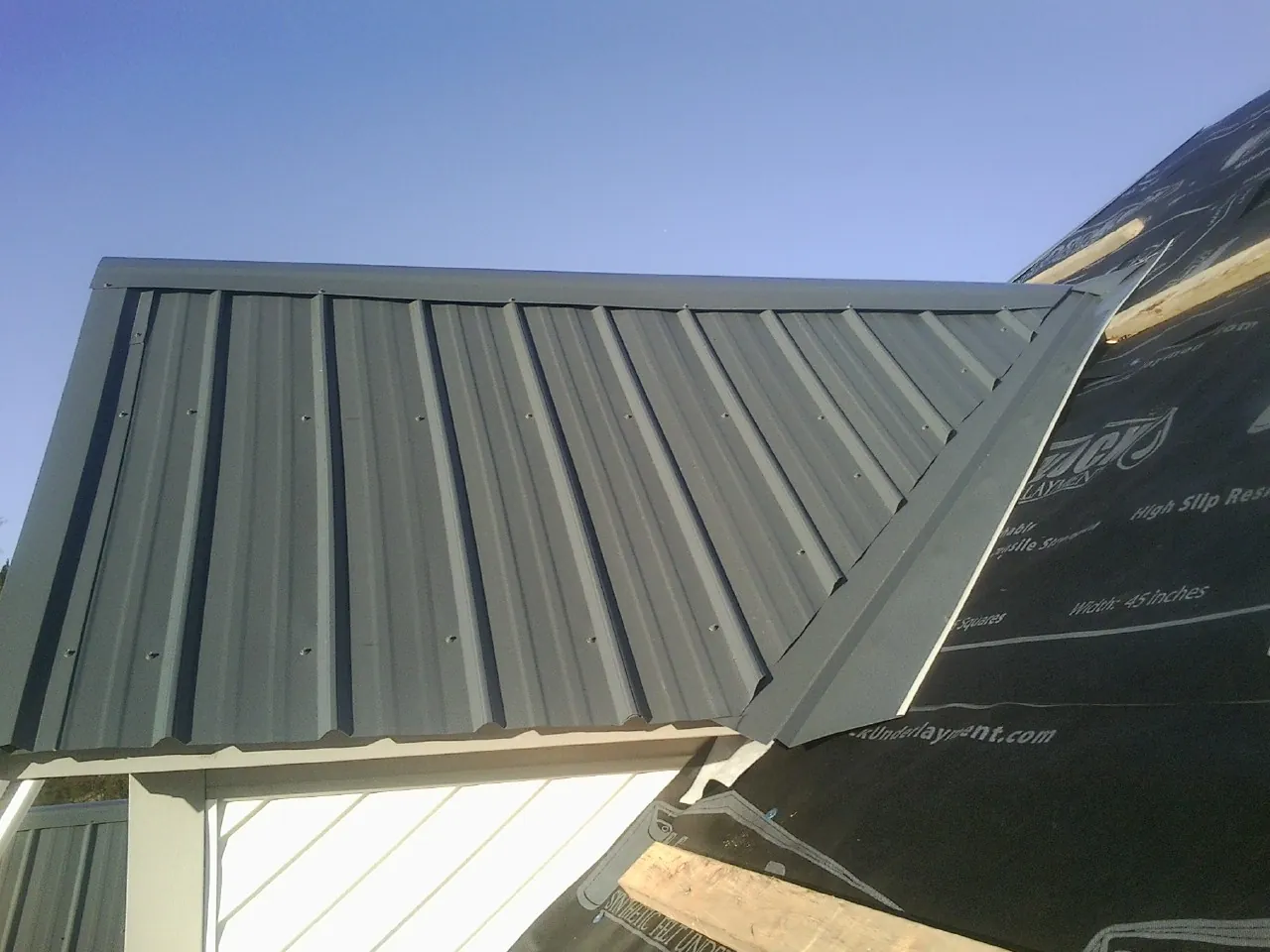 Gray metal roof panels going on over a garage gable in Elk City