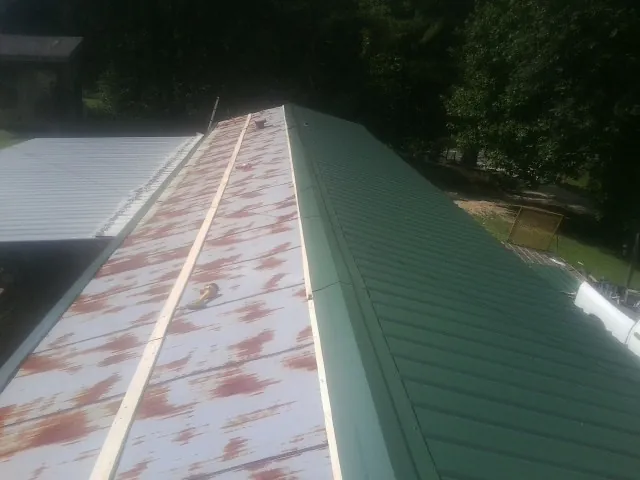 Old rusted panels beside newly installed green metal roofing — Wind Damage Roof Repair by Roofing Brothers in Elk City