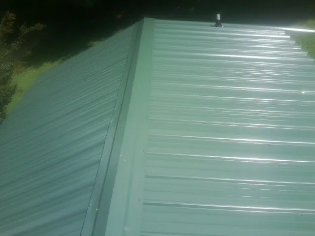 New green metal panels meeting at the ridge of a roof — Flat Roof Repair work by our crew in Elk City