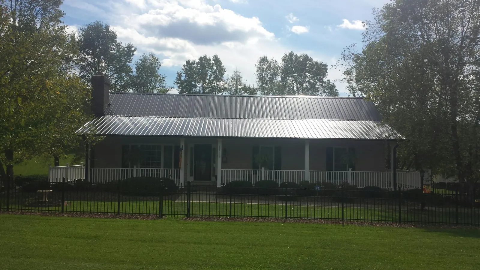 Gray metal roof on a brick ranch with a full width front porch — Gutter Guard Installation work by our crew in Elk City