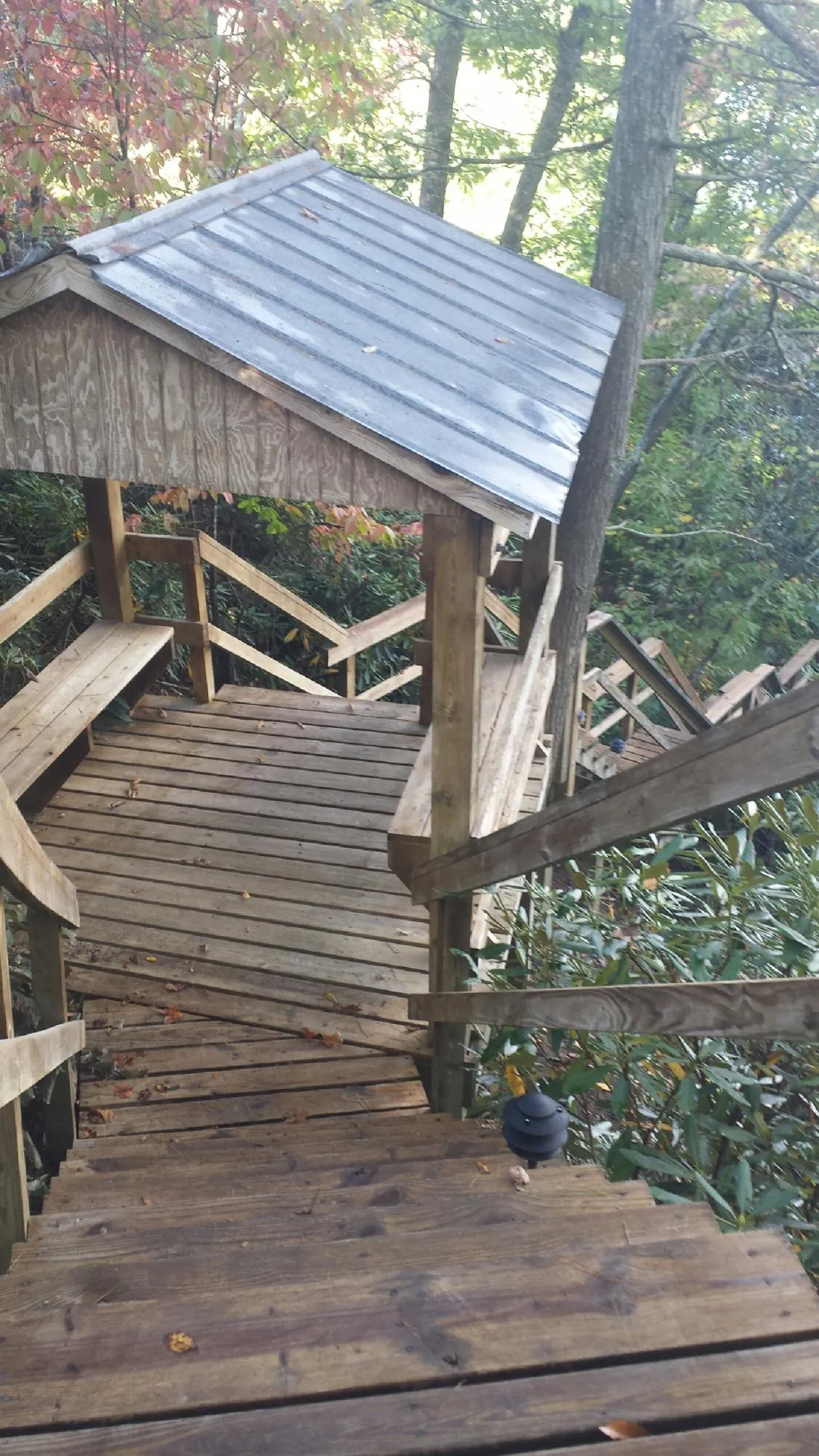 Metal roofed shelter over wooden steps on a wooded walkway — Skylight Repair & Installation work by our crew in Elk City