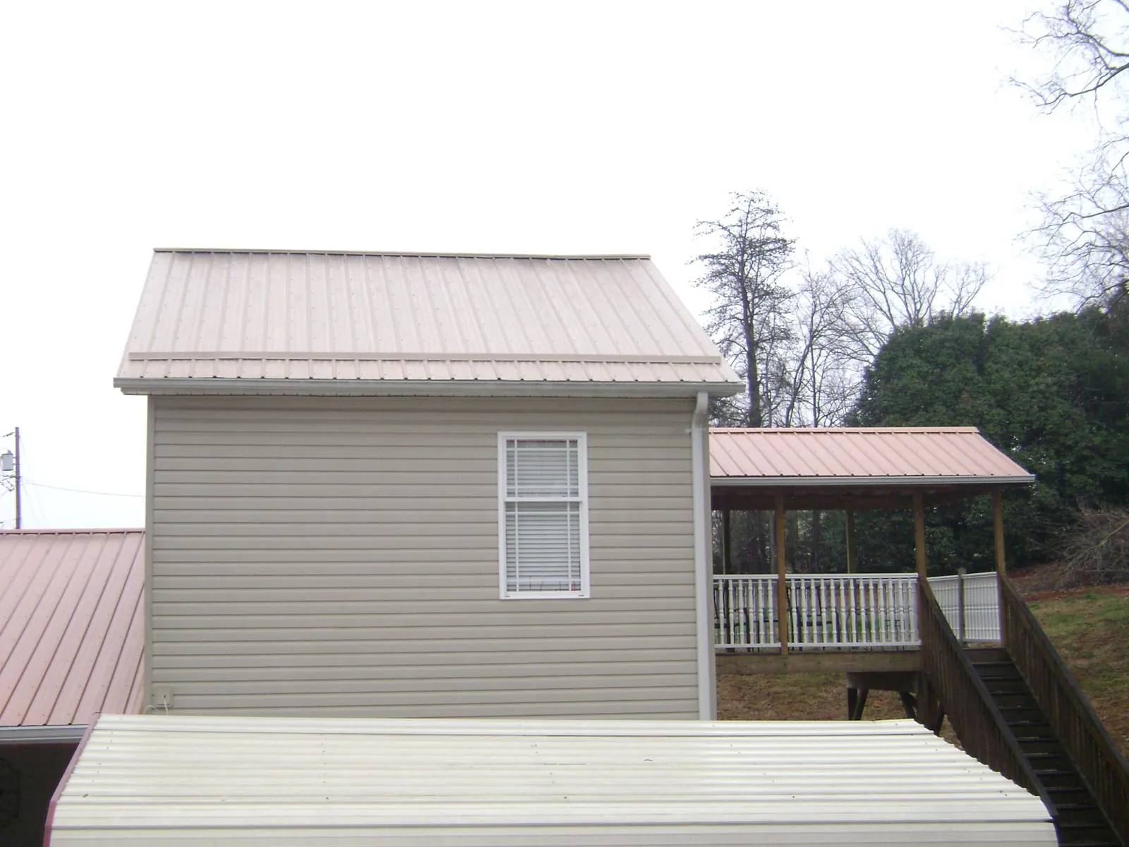 Tan metal roofs on a two story addition and attached porch, from a Roof Replacement job in Elk City