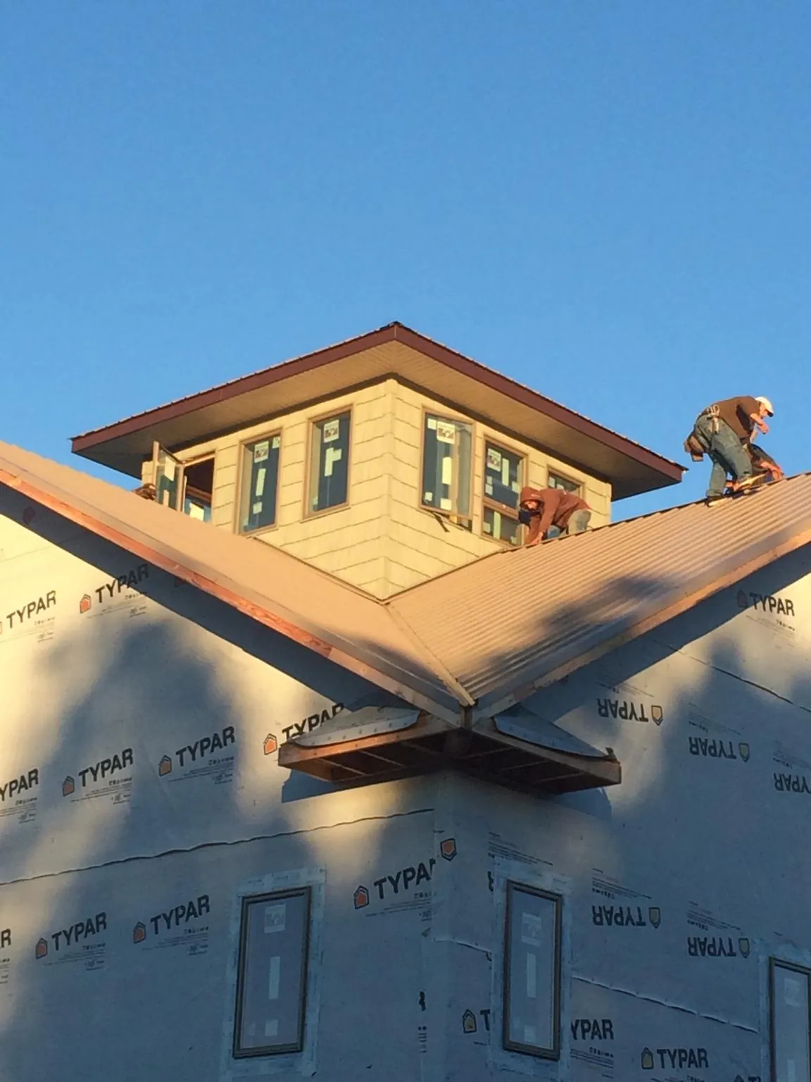 Roofers working around a rooftop cupola on a new metal roof at sunset — Roof Waterproofing in Elk City by Roofing Brothers